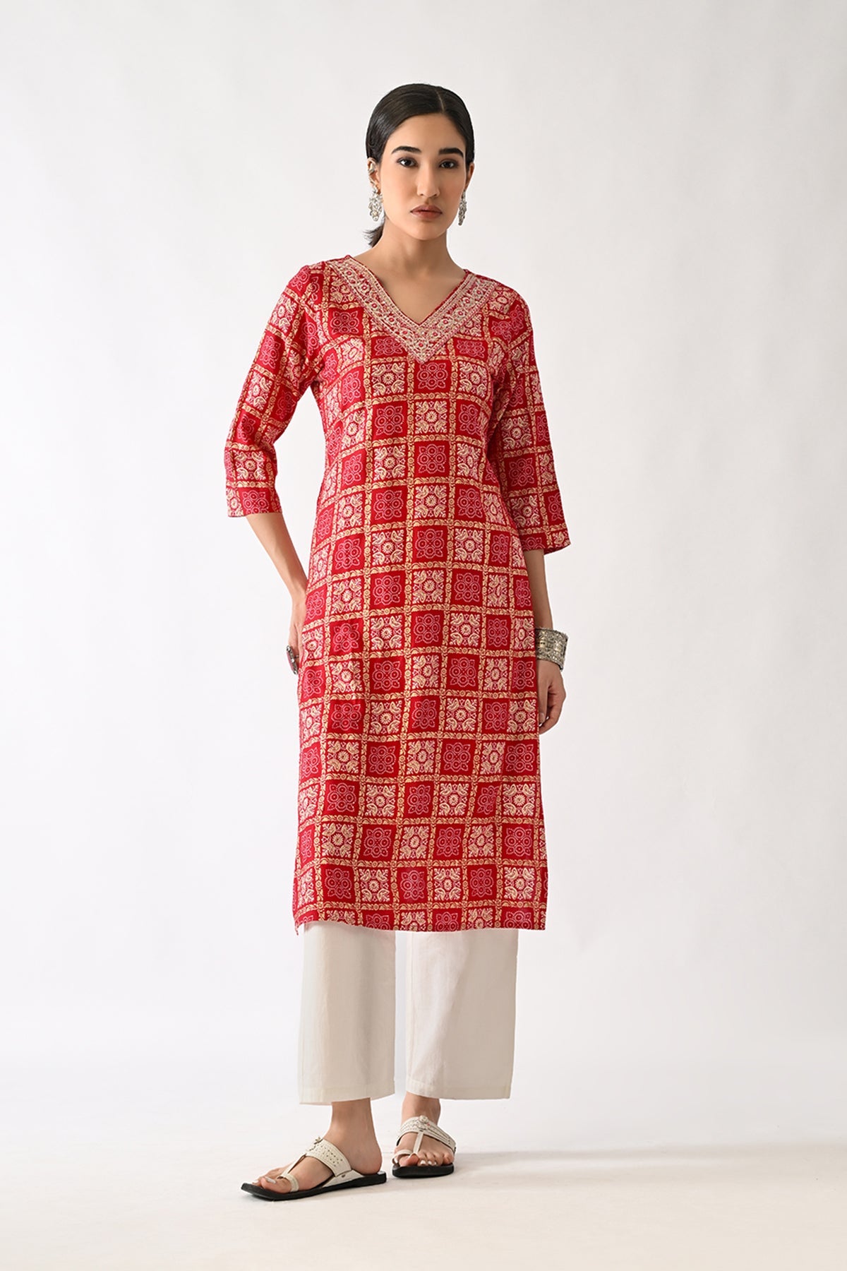 Woman wearing a red and white patterned kurta with white pants on a white background